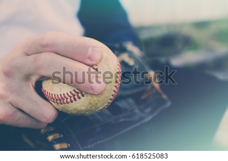 Baseball athlete holding old vintage ball in hand to make a pitch in summer sun.