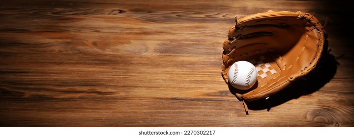 Baseball ball in a glove on the wooden table.