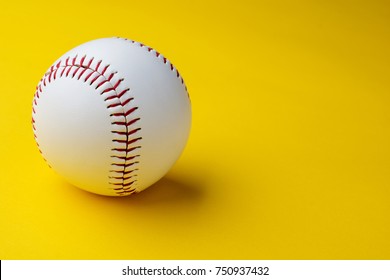 Baseball ball on yellow background with copy space.