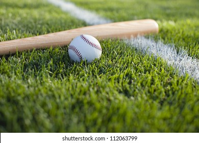 Baseball bat and ball near stripe on grass field