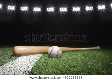 Baseball and bat at night under stadium lights on grass field with white stripe