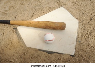 Baseball and bat on home plate of ballpark