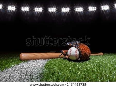 Baseball batt glove and ball low angle on grass field with stripe below lights at night