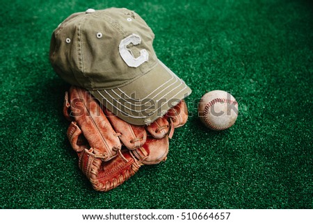 Baseball cap of captain, ball and leather catcher's glove.