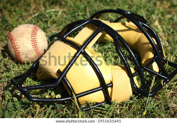 Baseball Catcher\'s mask\
and ball on grass