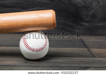 Baseball equipment: wooden bat and ball on a wood plank or bench background