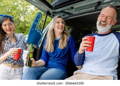 Baseball Fans Sitting And Drinking In The Car Boot At A Tailgate Party