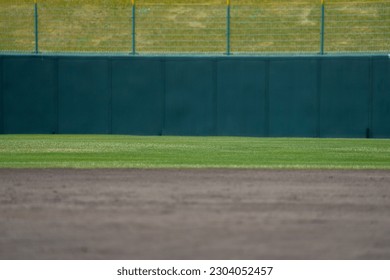 Baseball field outfield fence and outfield grass and ground black soil