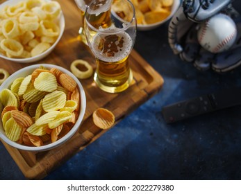 Baseball Glove With Ball, Beer, Chips, Snacks, TV Remote. Blue Background. Watching A Baseball Game With Friends, Family Vacation. Advertising, Poster, Banner. Low Angle View.