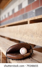 Baseball glove and ball sitting in a dugout.