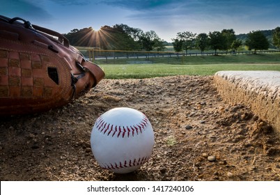 Baseball and glove on pitchers mound on early morning springtime