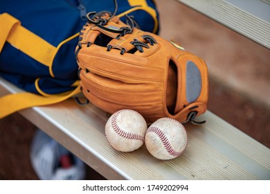 A Baseball Glove, Two Baseballs And A Duffle Bag On A Metal Bench In A Dugout