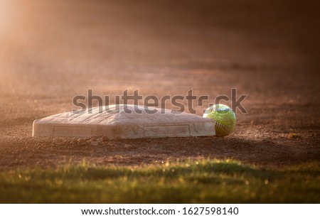 Baseball lies next to the base on the baseball field