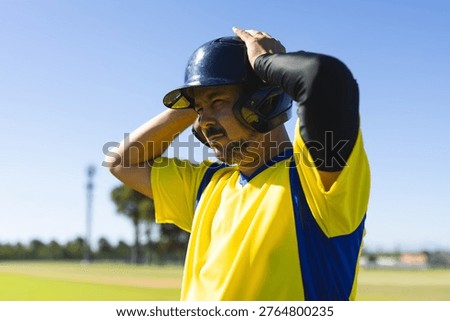 Baseball player adjusting helmet while preparing to bat on field, animated lines showing fit. Outdoor, athlete, amateur, outfield, infield, headgear, diamond