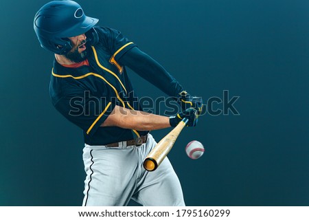 Baseball player with bat taking a swing on grand arena. Ballplayer on dark background in action.