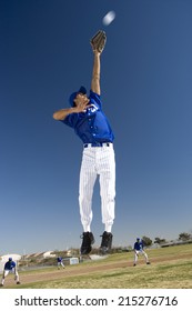 Baseball Player, In Blue Uniform, Jumping Up To Catch Ball In Protective Glove During Competitive Game (surface Level, Tilt)