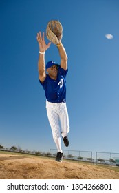 Baseball player diving to catch ball in protective glove during game