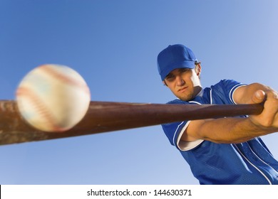 Baseball player hitting the ball with a bat against clear blue sky - Shutterstock ID 144630371