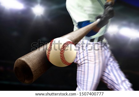 Baseball player hitting ball with bat in close up under stadium spotlights