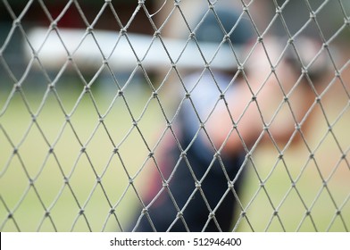 Baseball Player Out Of Focus Behind Baseball Cage Net.