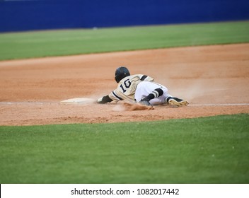 Baseball player sliding into the base during a game
