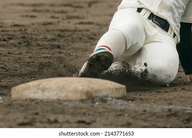 Baseball player sliding into a base while attempting to steal a base during a baseball game. - Powered by Shutterstock