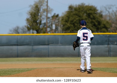 Baseball player taking the mound to pitch.