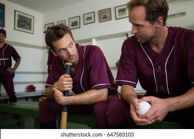 Baseball players sitting together on bench in locker room - Powered by Shutterstock