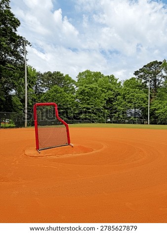 Baseball protective L-screen net on pitcher mound of infield dirt