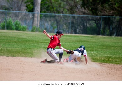 Baseball Shortstop Tagging Out A Player Sliding At Second Base.