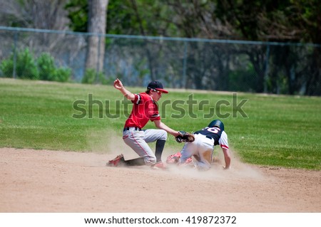 Baseball shortstop tagging out a player sliding at second base.