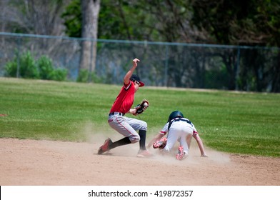 Baseball shortstop tagging a player out at second base that was sliding.