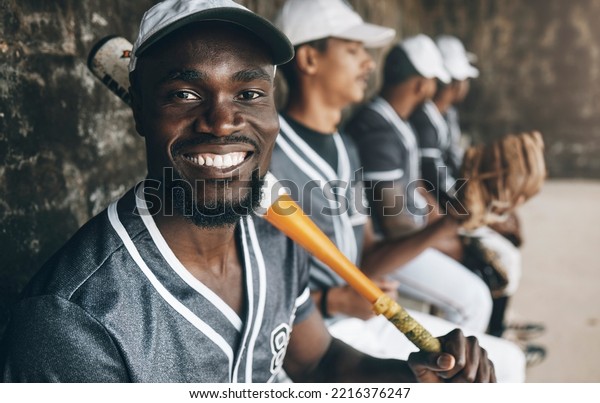 Baseball, sports and face with a man athlete\
holding a bat in a dugout with his teammates during a game or\
match. Portrait, happy and fitness with a baseball player sitting\
ready to play on the\
bench