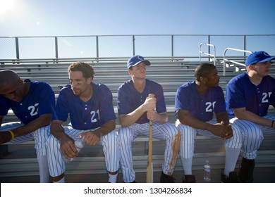 Baseball Team In Sitting On Bench In Stand During Baseball Game