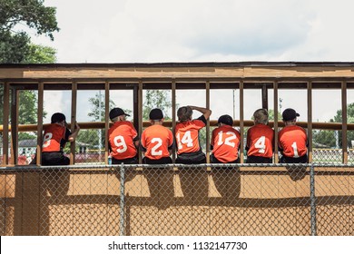 Baseball teammates in the dugout sitting on the fence - Powered by Shutterstock