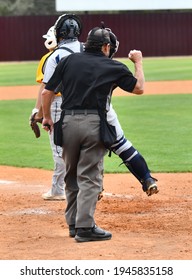 Baseball Umpire Calling Balls And Strikes At The Plate And Keeping The Home Plate Clean From Dust By Brushing It Off