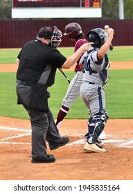 Baseball Umpire Calling Balls And Strikes At The Plate And Keeping The Home Plate Clean From Dust By Brushing It Off