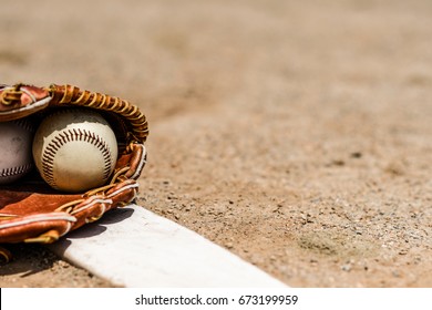 Baseballs in a glove in the dirt on a pitcher's mound - Powered by Shutterstock