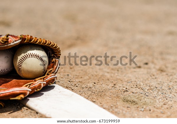 Baseballs in\
a glove in the dirt on a pitcher\'s\
mound
