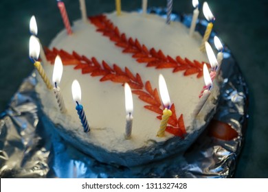 Baseball-themed birthday cake with candles lit on top. 