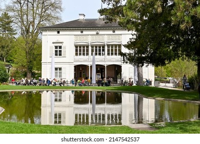 Basel, Switzerland - April 2022: People At The Cafe At The Rear Of The Villa Merian In The Merian Gardens, A Botanical Garden Near The City Centre