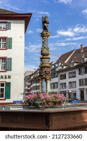 Basel, Switzerland - July 26 2021: Medieval Holbein fountain, built in 1550. On the top of column stands a bagpiper, which is said to have inspiration from the painter Albert Duerrer.