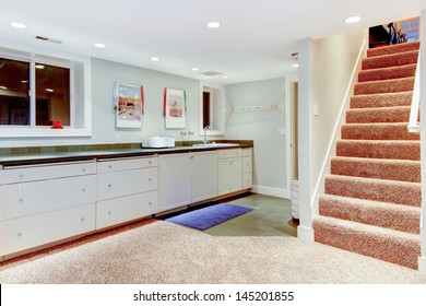 Basement With Staircase, White Cabinets For Storage.