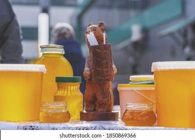 Bashkir bee honey poured into different containers with a figurine of a bear with a barrel in the middle