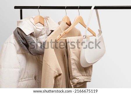 Basic autumn women's wardrobe concept on railing in showroom. Woman collection of clothes on a rack. Autumn fashion trending concept. Railing with stylish female clothes, clothing retails concept. 