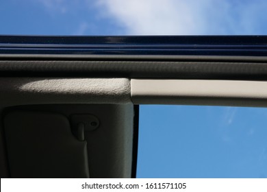 A Basic Car Door Metallic Frame, Showing Focus To The Rubber Cushion With Plastic Trim And Overhead Roof Fabric With A Blurred Interior And Blue Sky Background.