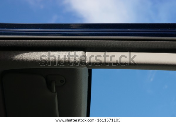A Basic Car Door Metallic Frame,\
Showing Focus to the Rubber Cushion with Plastic Trim and Overhead\
Roof Fabric with a Blurred Interior and Blue Sky\
Background.