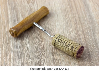 A Basic Corkscrew With A Cork On A Wooden Table. Name Of The Wine Country Chile Is Written On Cork.