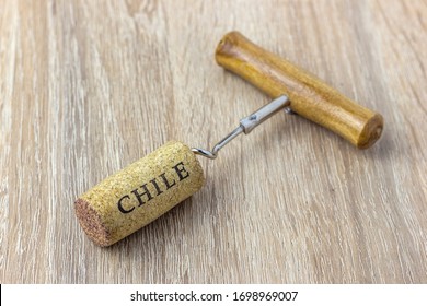 A Basic Corkscrew With A Cork On A Wooden Table. Name Of The Wine Country Chile Is Written On Cork.