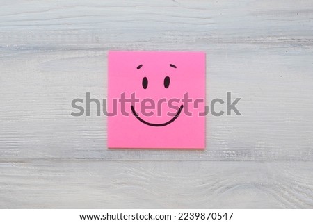 Basic emotion - joy or glad on square note on a light wooden background